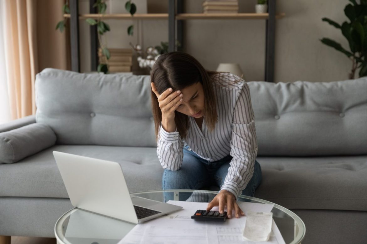 Uma pessoa sorrindo em frente a um notebook que mostra gráficos financeiros, ilustrando como usar IA para sair das dívidas e encontrar paz financeira.