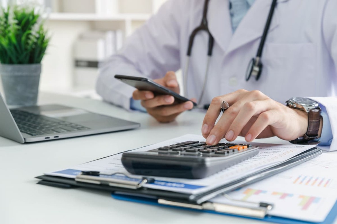 Um dentista sorridente em seu consultório moderno, olhando para um tablet que exibe um dashboard com gráficos de faturamento e agendamentos, ilustrando o uso de IA para clínicas.